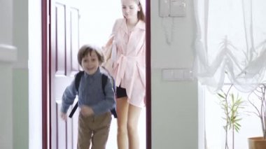 Güzel bir genç kız ve sırt çantalı küçük bir erkek kardeş eve giriyor. Çocuklar eve döndüğü için mutlu, çocuk gülümsüyor. Çocuklar yetişkinler gibi