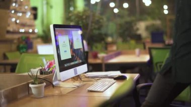 Gözlüklü genç adamın çalışma masasında bilgisayarla oturduğu yavaş çekim videosu. 