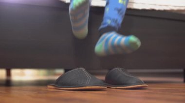 Bebek bacakları yataktan çıkar ve büyük ev terlikleri giyer.