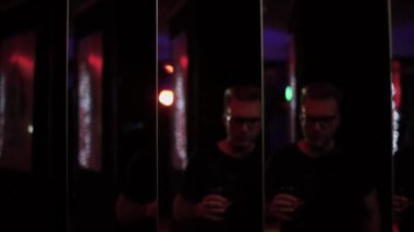 Bir bardak alkollü sakin adam diskoda eğleniyor. Gözlüklü adam aynaya bakıyor, sonra başını kameraya çeviriyor. Partiye katılanların boş vakitleri