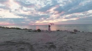 Pembe elbiseli, parlak makyajlı, nehrin kıyısında sis bombalarıyla dans eden tatlı bir genç kadın. Çiçekli, harika bir saç stili olan güzel, şehvetli bir kızın dansı. Yavaş çekim.