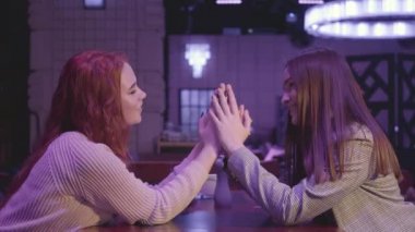 Mavi ışıkta el ele tutuşan iki güzel lezbiyen çiftin portresi. Kız arkadaşlar mutlu ve gülümsüyor. Lgbt aşk ve ilişki kavramı