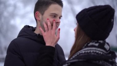 Genç bir kadın ve uzun bir adam kış parkında gözlerinin içine bakıyor. 