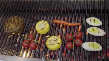 Şef, restoranın mutfağındaki ızgarada sebze pişiriyor. Modern restoranda ızgara et, mısır, kiraz domatesleri, limon otu ve kırmızı biber pişir. Yemek hazırlama.