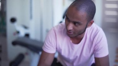 Erkek, spor salonunda konuşuyor. Eğitimden sonra Afraamerikalı adam dinleniyor. Adam sağlıklı ve güçlü olmak istiyor. İnsanların sağlıklı yaşam tarzı
