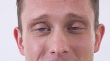 Kameraya bakıp gülümseyen mutlu ve çekici bir gencin portresini kes. Kapatın. Yarım yüz portresi.