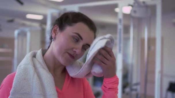 女性はジムで水を飲んでいる 額から汗をこすった若い女性 訓練の末女は休んでいる 人々の健康的なライフスタイル — ストック動画