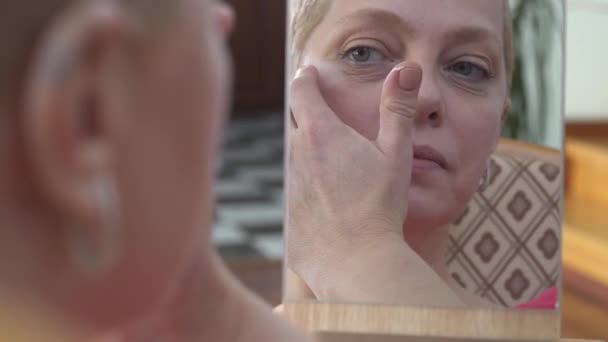 Reife Frau Anwendung Gesichtscreme Und Blick Auf Spiegel Video — Stockvideo