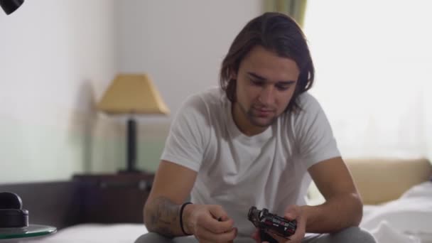 Junger Gutaussehender Kerl Mit Langen Haaren Sitzt Auf Dem Bett — Stockvideo