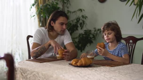 Két Jóképű Testvér Felnőtt Kisfiú Konyhaasztalnál Beszélgetnek Croissant Esznek Cappuccino — Stock videók