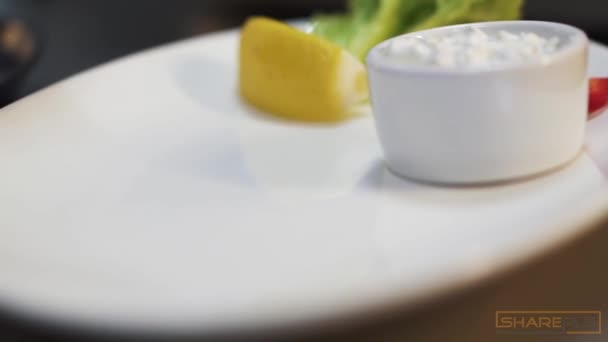 クックは 白いソース レモン コショウ レタスを閉じトングを使用してそれに横たわって大きなプレート上で調理サバ魚を置きます 近代的なレストランで提供する海の食べ物 — ストック動画