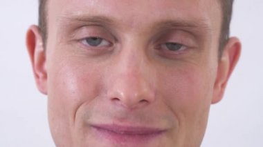 Kameraya bakıp gülümseyen mutlu ve çekici bir gencin portresini kes. Kapatın. Yarım yüz portresi.