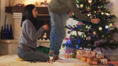 Genç pozitif çift Noel ağacını süslüyorlar. Yeni yıl videosu. 