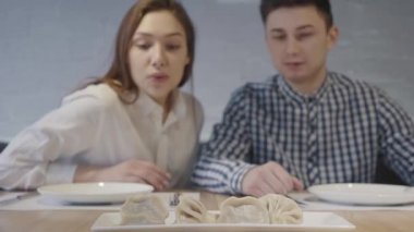 Önlerindeki masada duran khinkali köftesiyle ilgilenen pozitif bir çift. Erkek ve kadın modern kafede vakit geçirirler. Ön görünüm