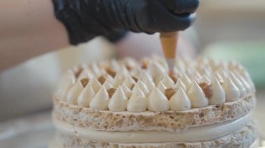 Üniformalı fırıncı leziz bir pasta süslemek için tatlı krema ya da kremalı muhallebi torbası koymuş.