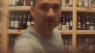 Kırmızı şarap içen bir adamın portresi. Adam bardağını kameraya çok yakın tutuyor ve sonra alkollü içkinin tadını alıyor. Sakallı neşeli erkek kameraya bakıyor.