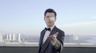 Genç profesyonel megisyen, beyaz tenis topuyla sihirli numaralar gösteriyor. Adam onu uzun renkli kurdelelere dönüştürüyor.