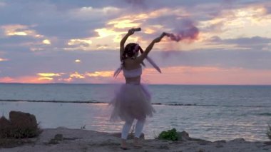 Açık havada sis bombalarıyla dans eden pembe elbiseli güzel bir kız..