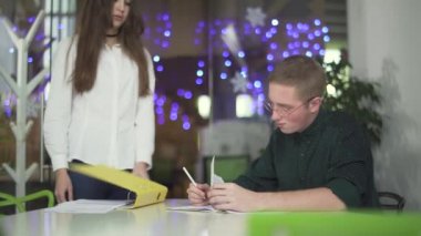 Modern ofiste çalışan gözlüklü güzel kız ve genç adamın iş konularını tartıştıkları video.