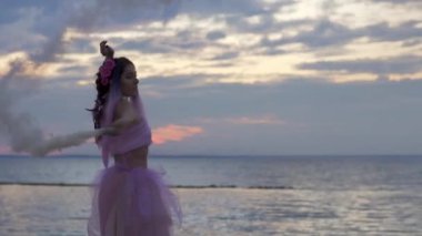 Açık havada sis bombalarıyla dans eden pembe elbiseli güzel bir kız..