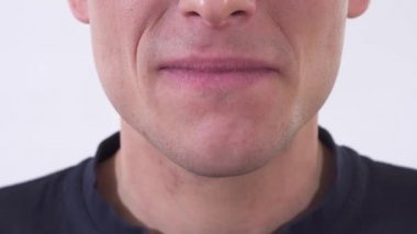 Deli adamın çenesini kapamak sağlıksız bir gülümsemeyle gülümsüyor. Beyaz bir arka planda stüdyoda çekim yapmak.