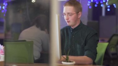 Ofisteki modern bilgisayarın önünde oturan adamın videosu.