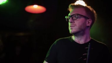 Gözlüklü, nargile tüttüren ve cep telefonuyla gece kulübünde yanıp sönen ışığın arka planına karşı mesaj atan çekici bir genç..