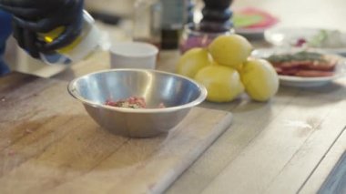 Siyah lateks eldivenli aşçının bedeni ton balığını terbiye eder, kaseye tuz ve kağıt koyar.