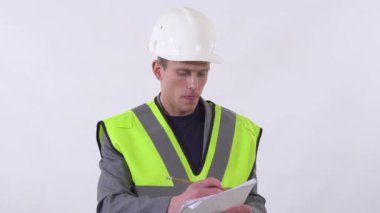 Üniformalı bir müteahhit portresi kağıda yazı yazıyor ve emirleri yakından veriyor. Genç mühendis işini yapıyor. Beyaz bir arka planda stüdyoda çekim yapmak.