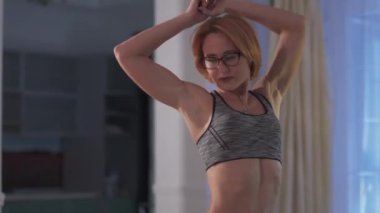 Kız pompalanmış göbeğini gösteriyor. Gözlüklü, kısa kızıl saçlı çekici bir kadının kesilmiş fotoğrafı evde spor kıyafeti giyiyor..
