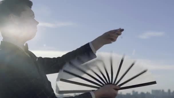 Young Professional Magician Waving Fan Blowing Shiny Papers His Hand — Stock Video