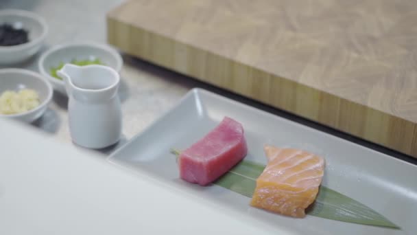 在餐馆厨房的长盘子里放着几片美味的鲑鱼和金枪鱼 准备上桌 健康的食物在一个现代化的餐厅 特写镜头 有酱汁的小罐子就在附近 — 图库视频影像