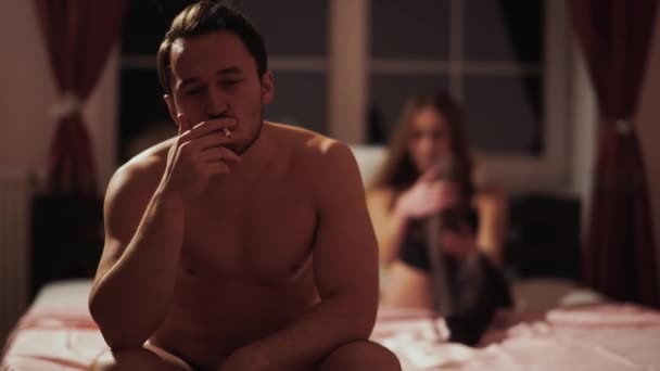 Jovem Cara Feliz Fuma Sentado Cama Contra Fundo Uma Bela — Vídeo de Stock