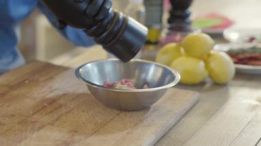 Siyah lateks eldivenli aşçının bedeni ton balığını terbiye eder, kaseye tuz ve kağıt koyar.