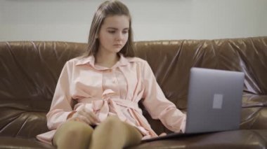 Dizüstü bilgisayarın önündeki deri koltukta oturan güzel kız. Modern bir gencin boş vakitleri. Aletlere bağımlılık. Sağlık konsepti, zengin hayat.