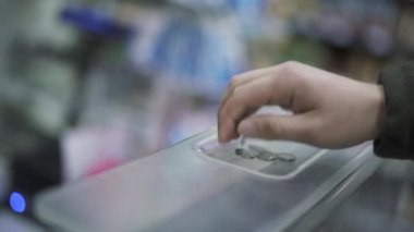 Alıcının ve satıcının elleri yakın plan. Alıcının eli parayı koyuyor ve satıcının eli de parayı yakın plan çekiyor. Ödeme mağazadaki kasada..