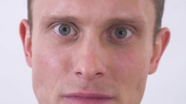 Gri gözlü delinin suratını kapat ve kameraya öfkeyle bak. Adam depresyonda, hayal kırıklığına uğramış yüzü kızgın görünüyor, üst dudak yukarı çıkıyor. Beyaz bir arka planda stüdyoda çekim yapmak.