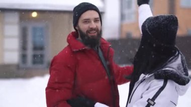 Genç pozitif çiftin arka bahçede, yağan karın altında büyük bir evin önünde gülüşlerinin videosu.
