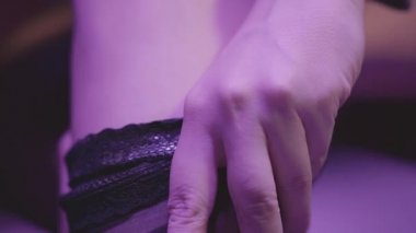 Genç bayanın eli yavaşça ince bacağına siyah çorap giydi. Bayan gece eğlencesi için hazırlanıyor. Erotik aksesuarlarda seksi bir kız.