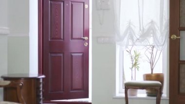 Genç güzel kız bir kapı aç ve eve gel büyük okul çantası taşıyan yorgun küçük kardeşinle.