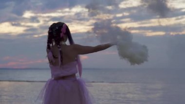 Açık havada sis bombalarıyla dans eden pembe elbiseli güzel bir kız..