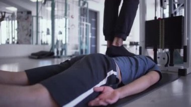 Erkeklerin bacakları, spor salonunda erkeklerin sırtına basıyor. Bir adam diğerinin üzerine basarak masaj yapıyor. Gençlerin sağlıklı yaşam tarzı