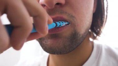 Beyaz arka planda mavi diş fırçasıyla dişlerini fırçalayan insanlar.