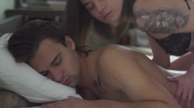 Yakışıklı adam göbeğinde yatıyor. Kadın onun üzerine uzanır, parmaklarını nazikçe sırtına bastırır. Güzel bir çiftin romantik ilişkisi.