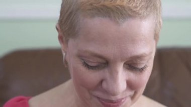 Olgun bir kadın evde pamuk pedlerle, kaplıcalarla, videoyla yüzünü temizliyor. 