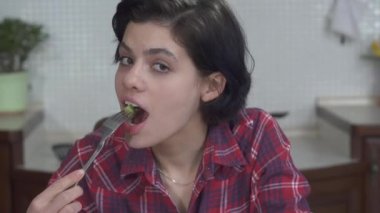 Domates ve sebzelerle taze salata yiyen ve zevk alan güzel bir genç kızın portresi. 