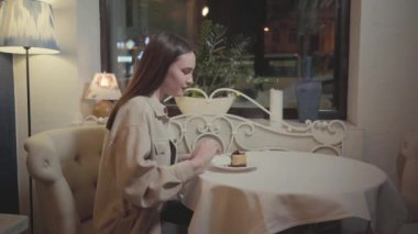 Güzel bir restoranda ağız sulandıran çikolatalı cheesecake ya da tiramisu yiyen tatlı genç bir kız.