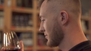 Bardakta şarap kokusu alan yakışıklı bir erkek portresi. Profildeki adam alkollü içeceğe hayran. Müşteri içki dükkanında.