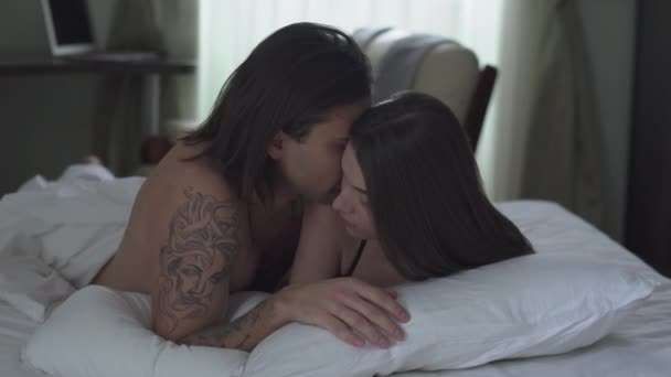 Όμορφος Άντρας Αγκαλιάζει Κορίτσι Του Ξαπλωμένο Στο Κρεβάτι Και Φιλάει — Αρχείο Βίντεο