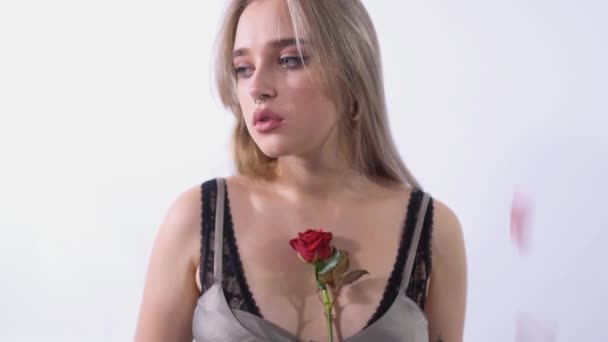 鼻を突かれた悲しい少女の肖像画は 彼女の顔の上にバラを実行します バラの花びらが上から注ぎ ビデオ — ストック動画